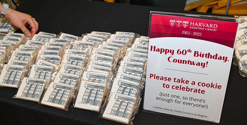 Wrapped cookies decorated with a line drawing of Countway Library arranged on a table next to a sign that reads, “Happy 60th birthday, Countway! Please take a cookie to celebrate.”