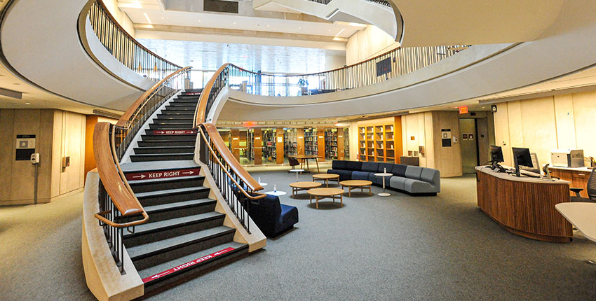 The interior of Countway Library, showing the renovated lower level and a curving staircase leading to upper levels.