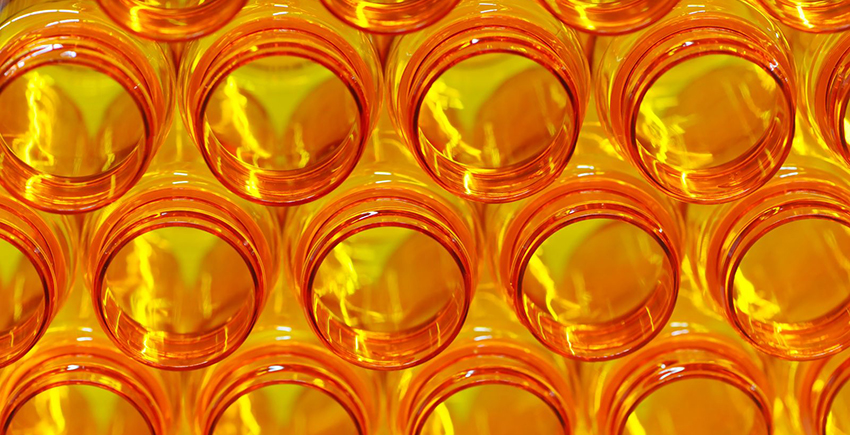 A stack of open orange prescription medicine bottles, glowing with backlight and lightning-shaped highlights.
