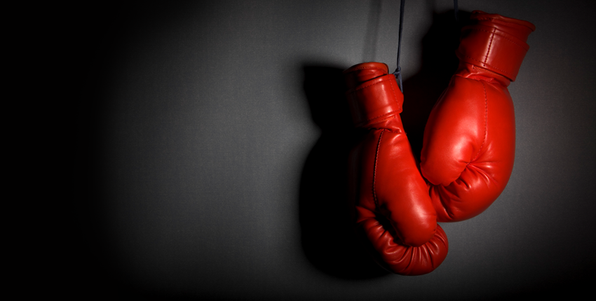 A pair of dramatically lit boxing gloves hanging on a wall