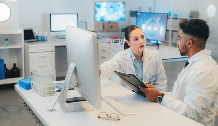 two people in white lab coats discussing a chart