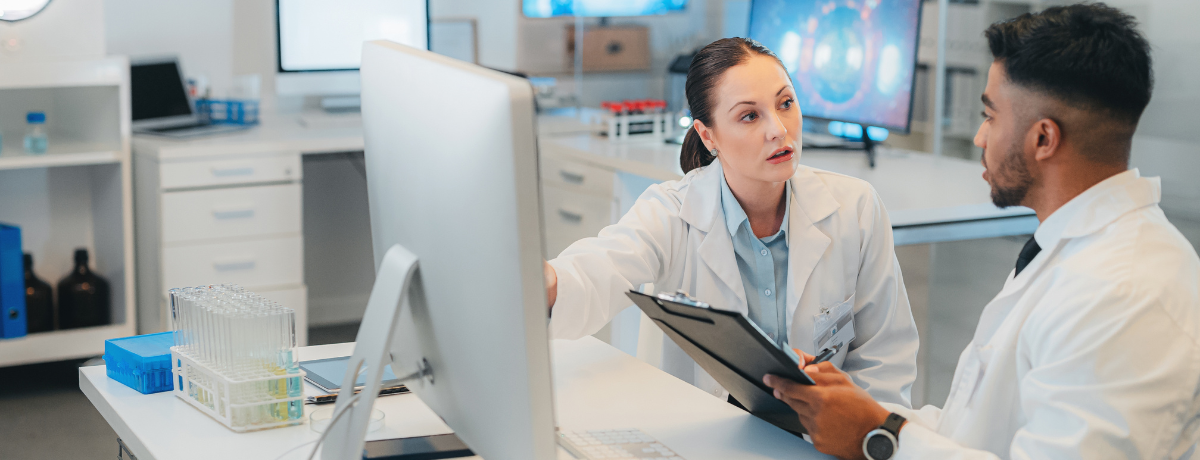 two people in white lab coats discussing a chart