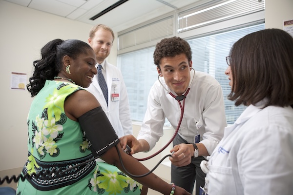 A medical student is practicing the physical exam on a patient with two preceptors.
