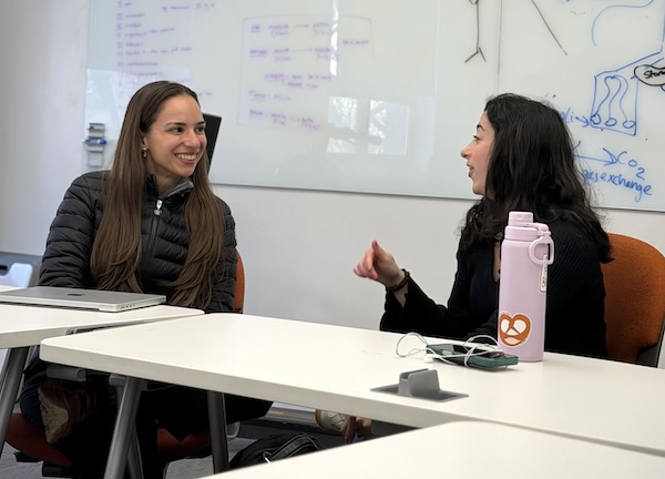 Two MD students chat in a classroom setting