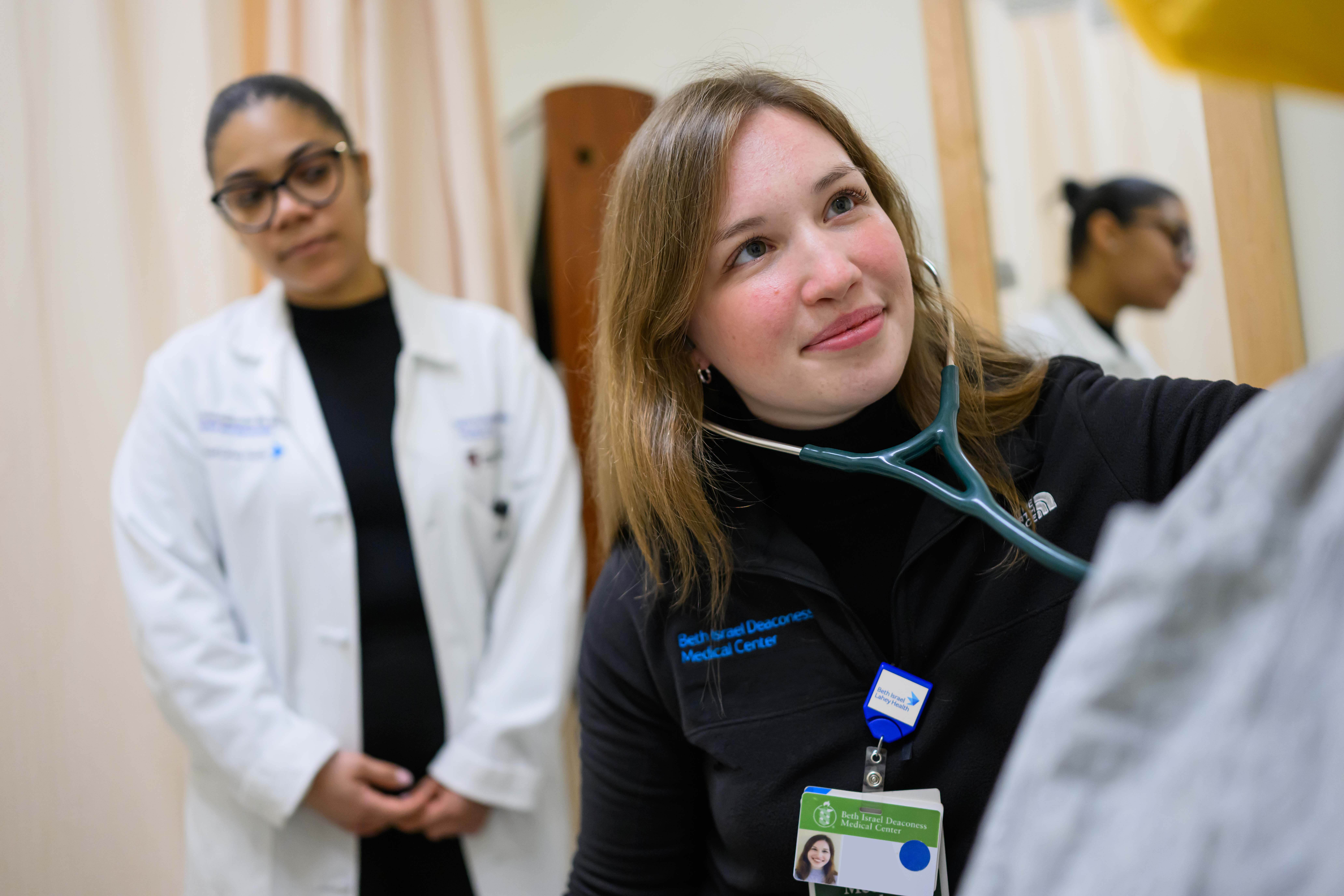 Image of an HMS student practicing a medical exam with a mentor observing near by