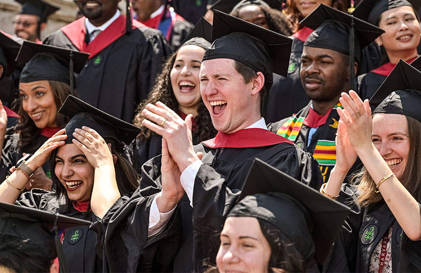 Tight crop of a group of about a dozen grads clapping and smiling.