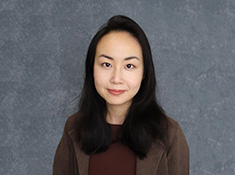 A woman with a brown top on a gray backdrop