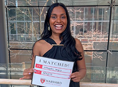 A woman smiles holding a sign that says I Matched!