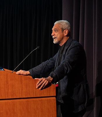 Side view of Vikram Patel speaking at a lectern