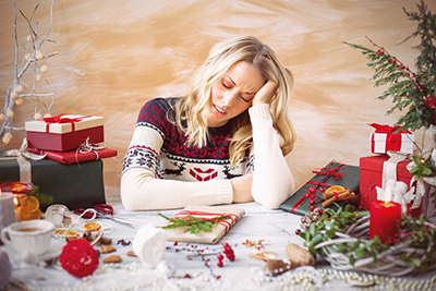 a woman with a festive sweater on with her head tilted and in her hands. 