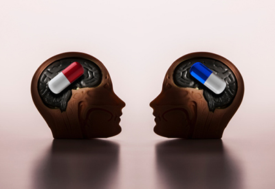 a side profile view of two human head graphics, the left has a red and white pill within the brain the right has a blue and white pill within the brain. 