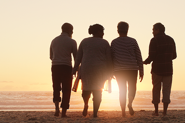group of people walking on a beach at sunset
