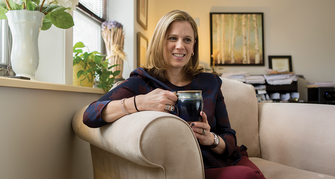 Kimberly Pearson seated on a couch holding a coffee mug