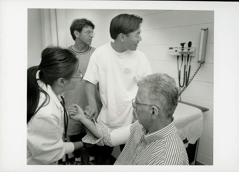 Trio of individuals in a clinic settings, a fourth person as patient