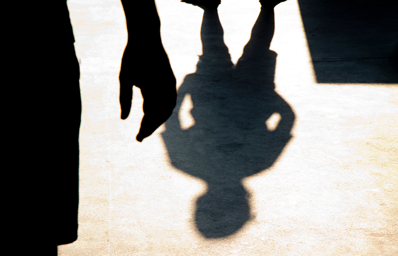 shadow of a person in a threatening pose, confronting a young person