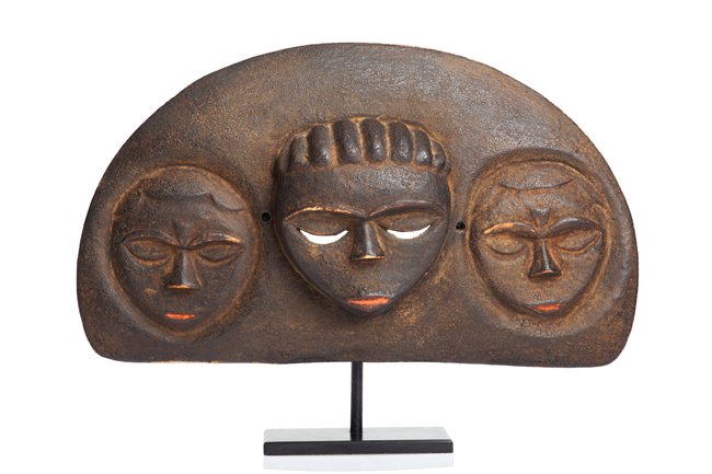 three masklike faces on a half-moon sculpture fixed on a pedestal 