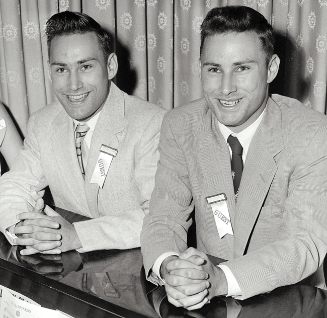 two young men in suit coats seated at a table