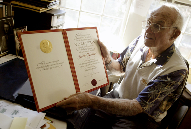 gray-haired man holding a certificate decorated with a gold seal