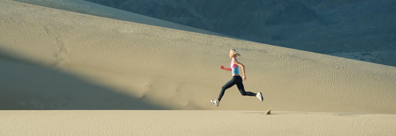 woman running along sand dunes