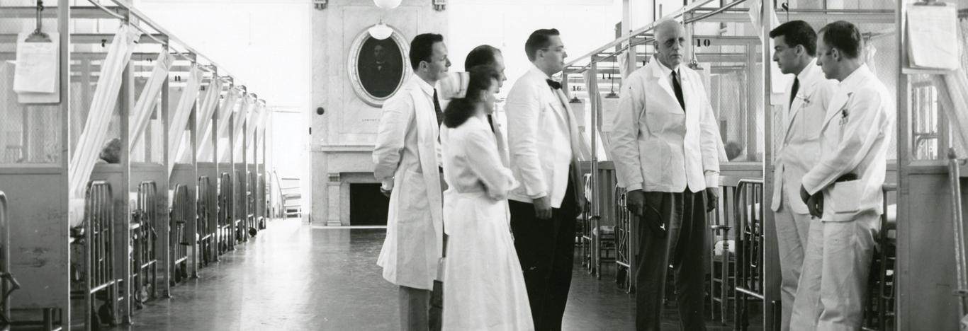 Medical staff and faculty talking in a hospital ward, mid-20th century