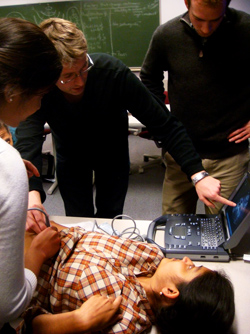 During one of the practical skills sessions for students in the new course on global health, Mitalee Patil performs ultrasound on Isha Agarwal. David Shulman (right) observes while instructor Tobias Kummer (of Brown University) explains the basics of portable bedside ultrasound. Photo by Brett Nelson.