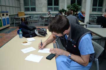 Thomas Heyne, clinical fellow in Pediatrics at MGH, signs his own notes of gratitude in Courtyard Café. Photo by Lindsey Bourcier 