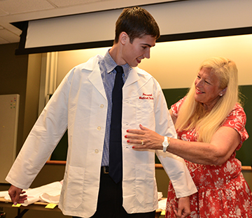 A student in the Francis Weld Peabody Society receives his new white coat. Image: Steve Lipofsky