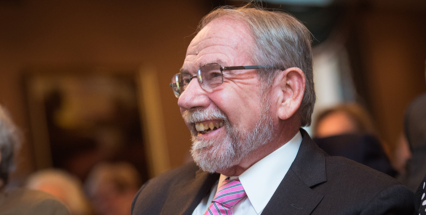 Gray-haired, bearded man with glasses, smiling