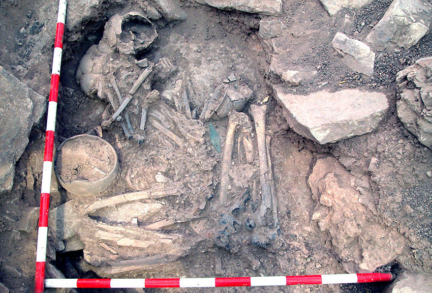 Two skeletons in an exhumed gravesite, with scale bars