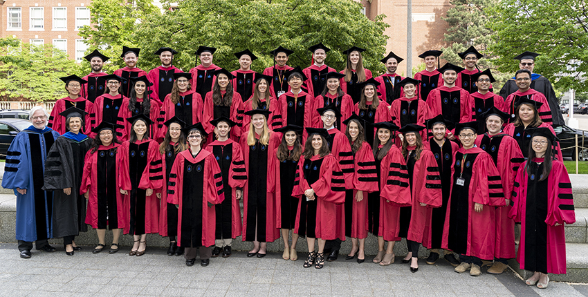 Dozens of new PhD recipients stand outside