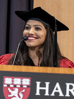 Young woman of South Asian descent smiling at podium