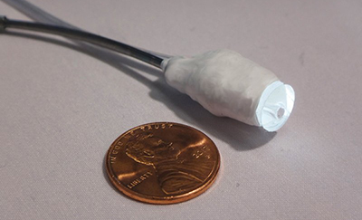 Close-up of catheter tip next to a similarly sized penny