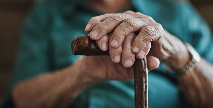 close up photo of a senior man's hands on a cane