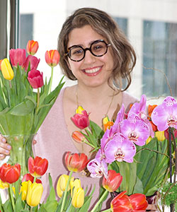 Head shot of Azhir with bouquets of colorful flowers