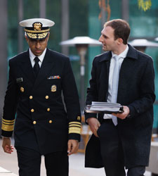 Murthy in uniform seated at table looking at laptop with Beckman to right leaning in; a backdrop behind them reads The White House