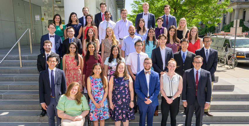 Group of the HST grads in plain clothes on steps on the MIT campus