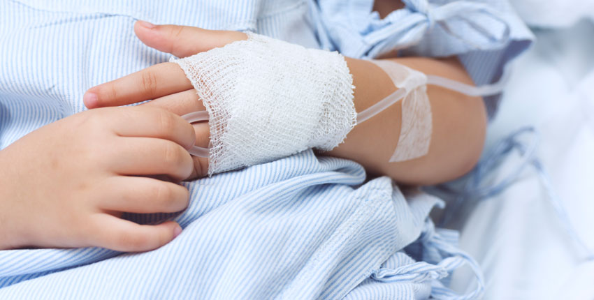 close up shot of a child's hands, one with an IV inserted 