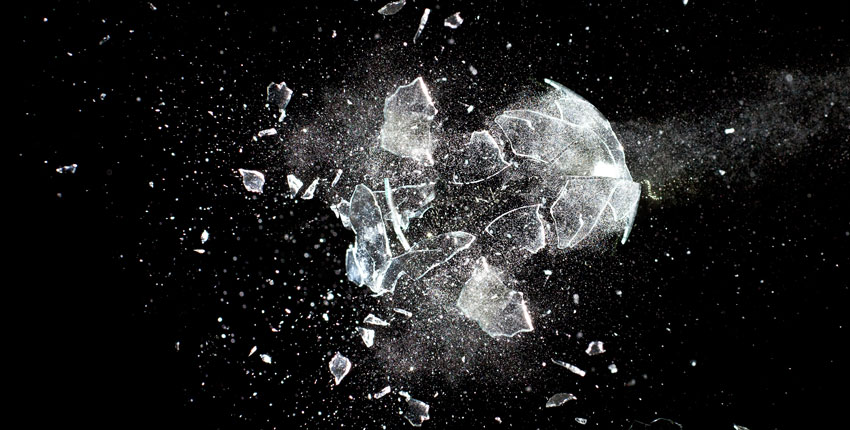 A piece of glass being destroyed against a black background