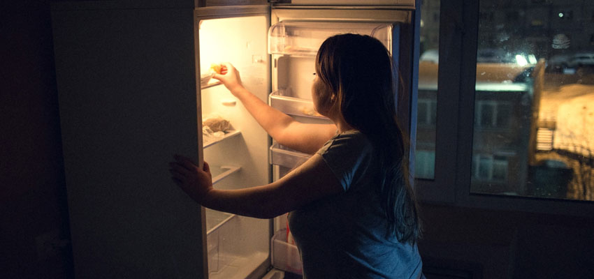 Woman getting something out of the refrigerator during the night