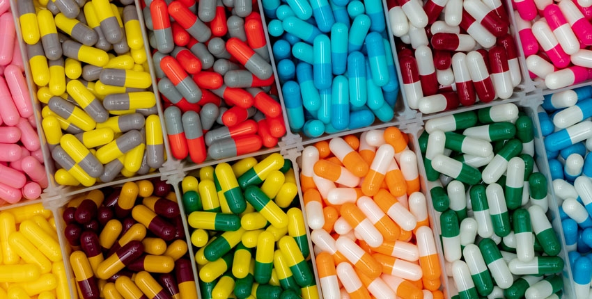 Multiple rectangular compartments filled with large, multi-colored pills