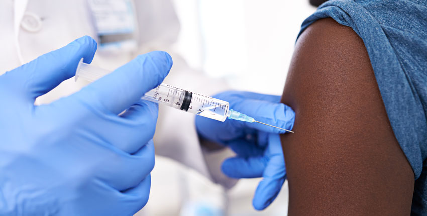 A closeup of a gloved healthcare provider injecting a vaccine into a patient's arm