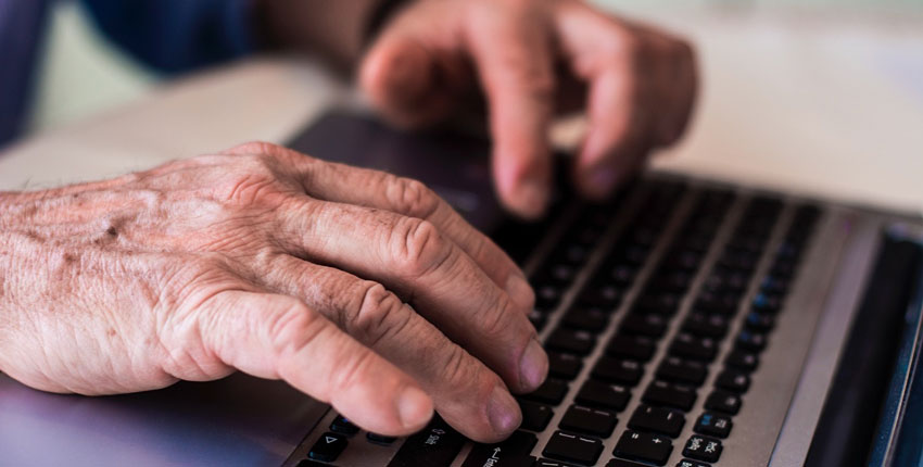 Photo of an older persons hands on a laptop keyboard 