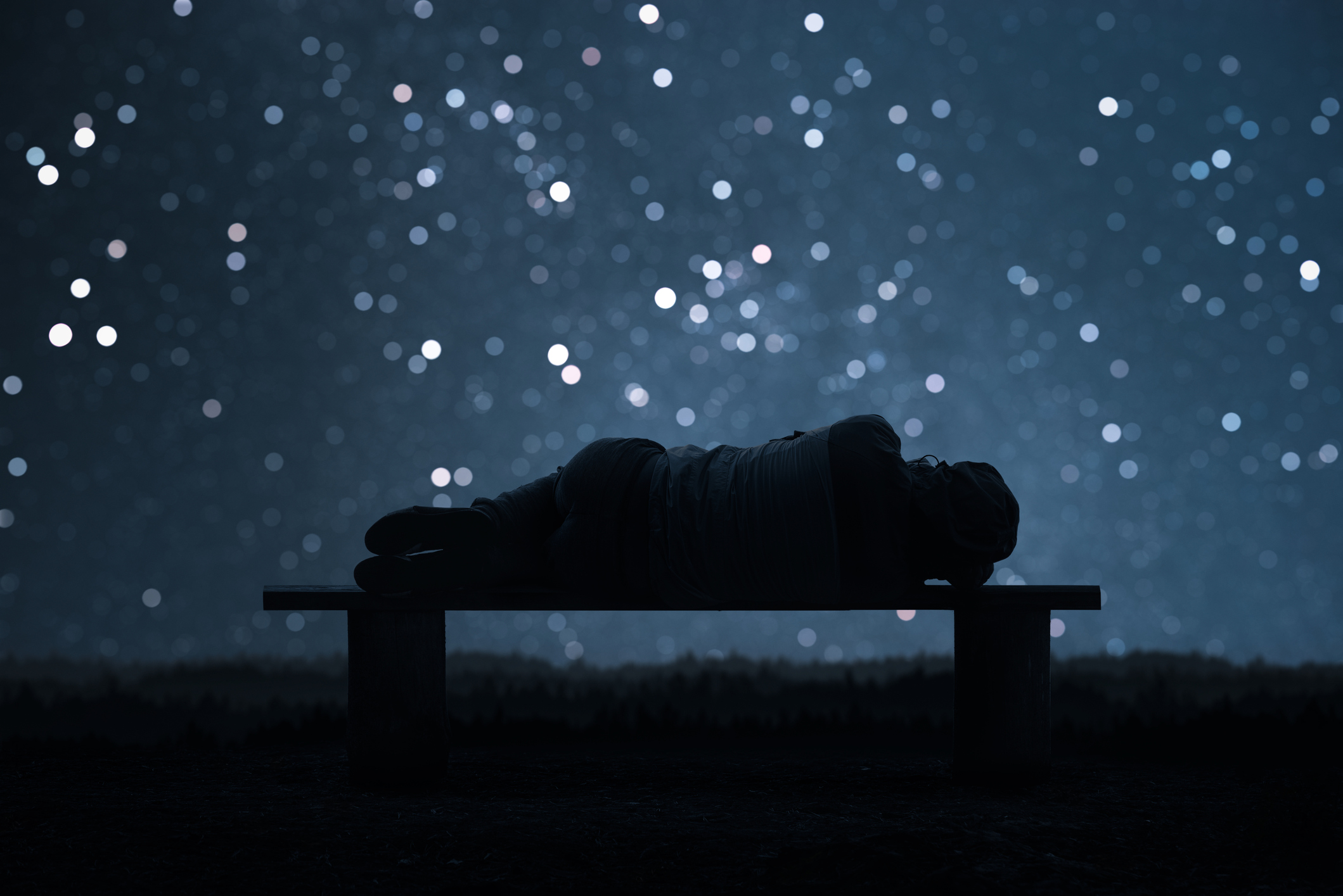 Photo illustration of a sleeping female form in silhouette with a backdrop of a night sky and stars