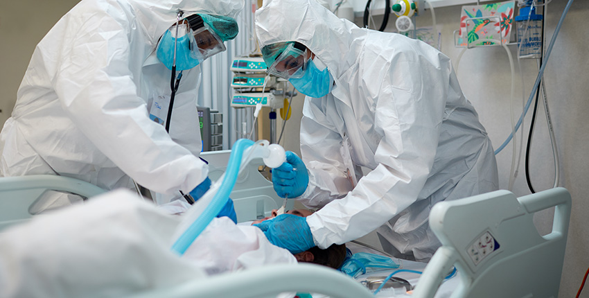 two health care workers intubating a patient with covid-19