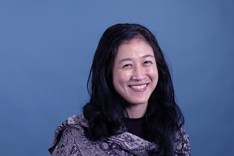 Head shot of a smiling woman against a solid blue backdrop