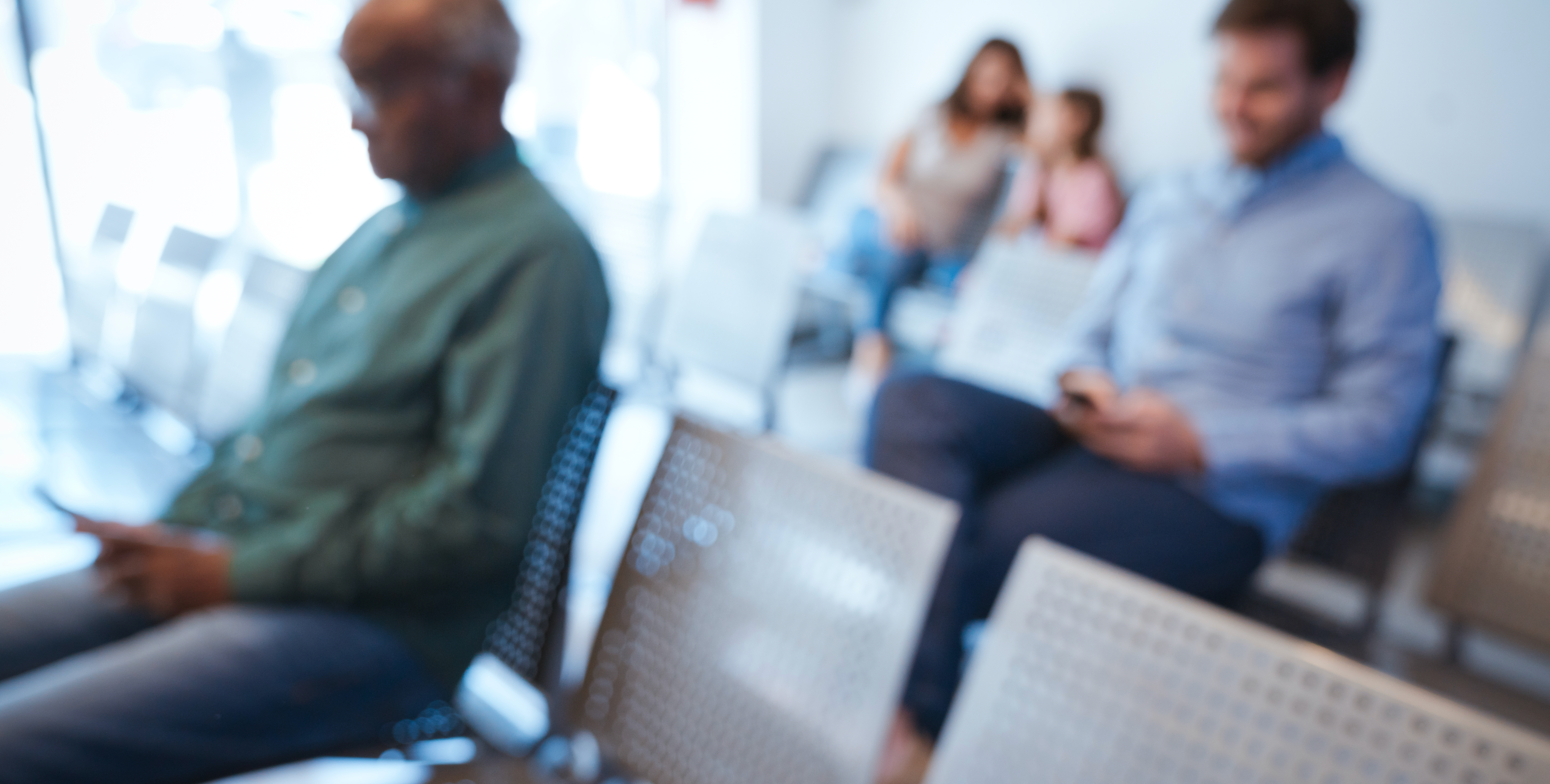 A blurry image of people in a waiting room.