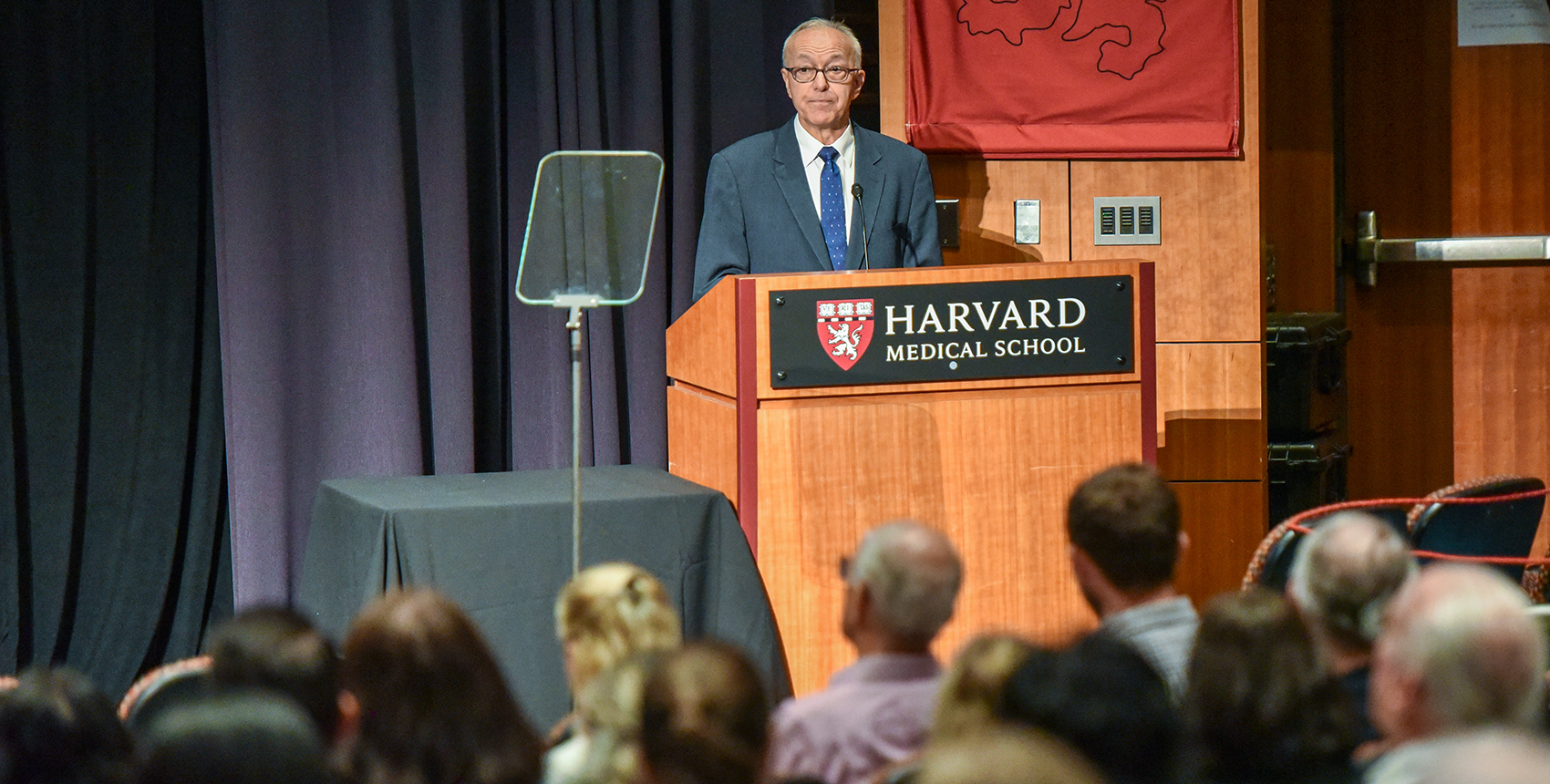 A person standing at a podium with a crowd of people watching