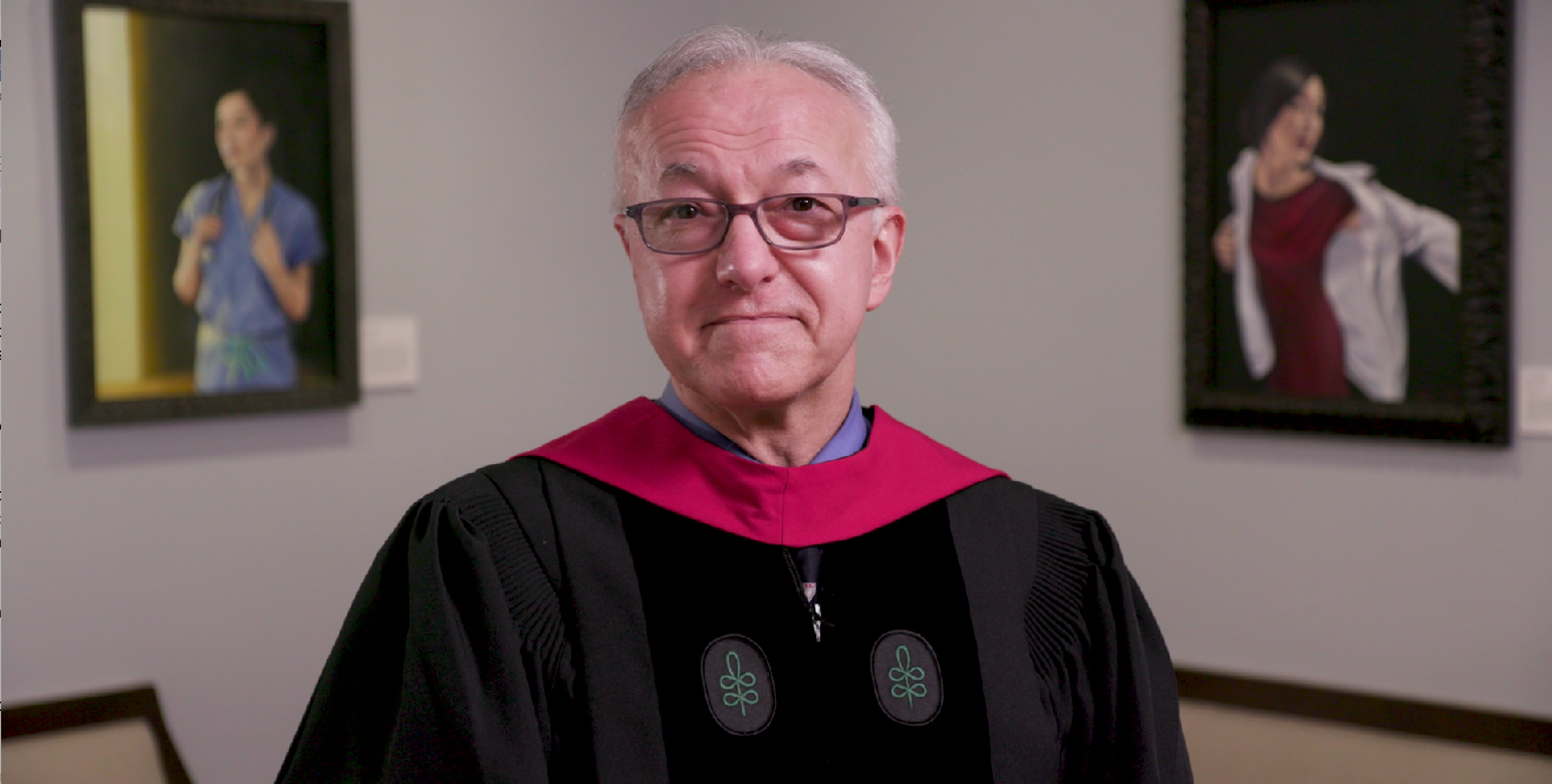 Dean Daley, wearing academic regalia, speaking in Gordon Hall