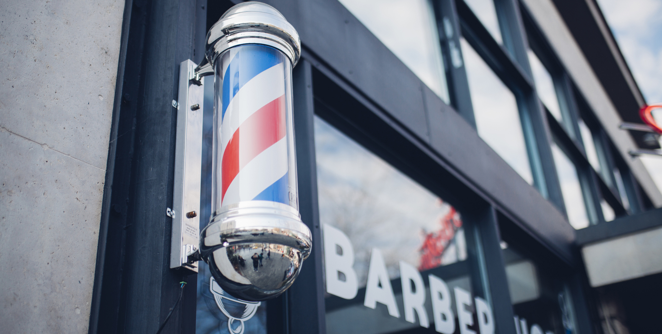 Photo of striped barbershop pole mounted on door of shop