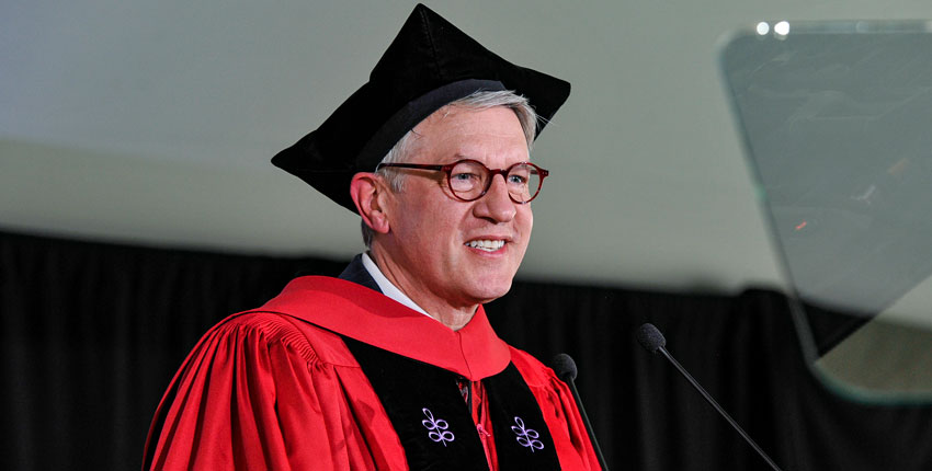 Giannobile wearing regalia speaking into microphone